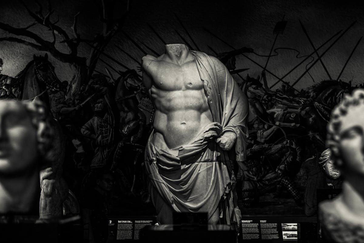 Classical white marble torso and flanking carved heads displayed against a darker backdrop, illustrating the quality of stone and finish the local studios produce